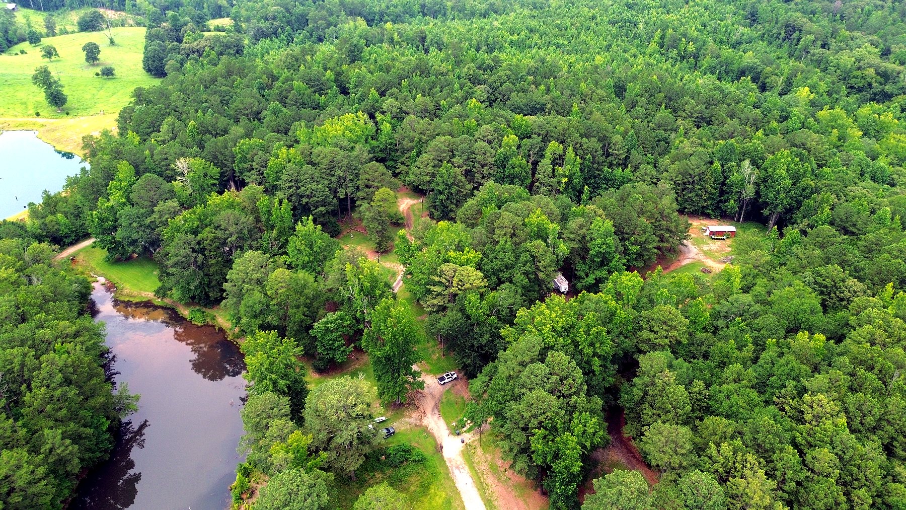 Aerial view of wooded campground land and pond near Lake Martin